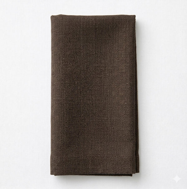 A neatly folded Amelia Brown Linen napkin rests on a light, solid surface.