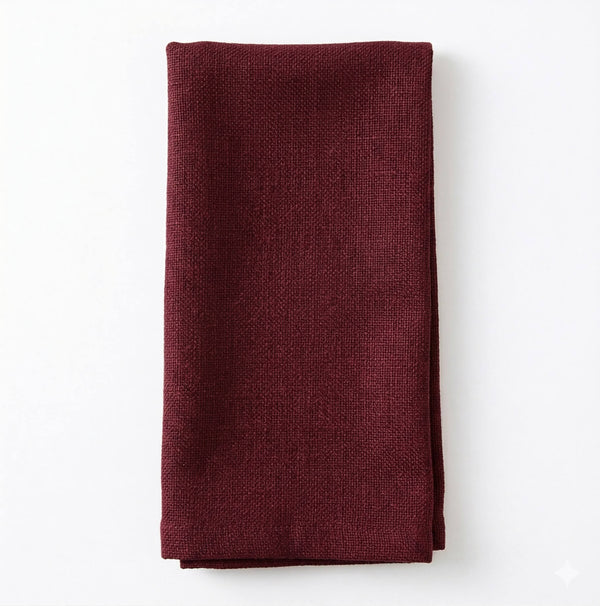 A neatly folded Amelia Burgundy Linen napkin, crafted from elegant fabric, rests on a white surface—ideal for an upscale event.