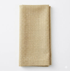 A neatly folded, textured beige Amelia Champagne Linen napkin rests on a plain white background.