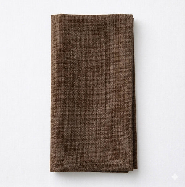 The Amelia Chocolate Linen is a neatly folded brown linen napkin with a textured finish, elegantly displayed on a plain white surface.