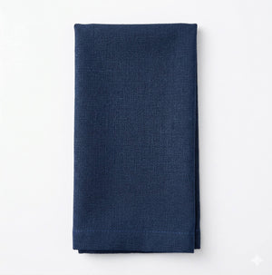 A neatly folded Amelia Dark Blue Linen napkin, made from elegant fabric, lies on a plain white background.