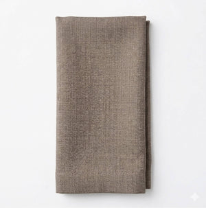 A neatly folded, textured brown Amelia Dark Crème Linen napkin is displayed against a plain white background, ideal for an elegant event setting.