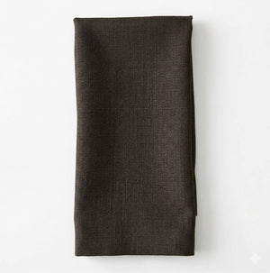A neatly folded dark green Amelia Linen napkin is laid on a white surface.