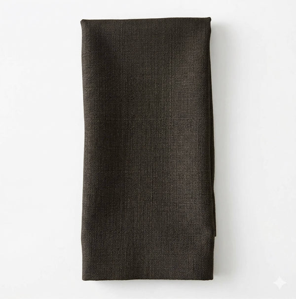 A neatly folded dark green Amelia Linen napkin is laid on a white surface.