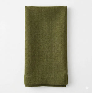 A neatly folded Amelia Grass Green Linen napkin, made of elegant textured fabric, is displayed on a plain white background.