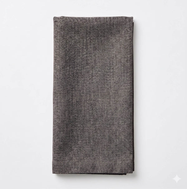 The Amelia Grey Linen napkin, featuring a textured dark gray fabric, is neatly folded and displayed on a plain white background—an ideal elegant accent for any event setting.