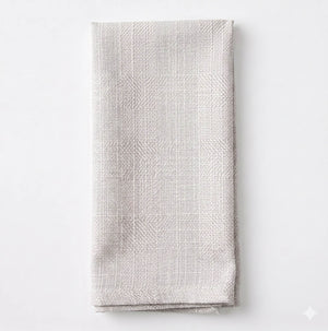 The Amelia Ivory Linen napkin, neatly folded and crafted from elegant textured fabric, is displayed on a plain white background.