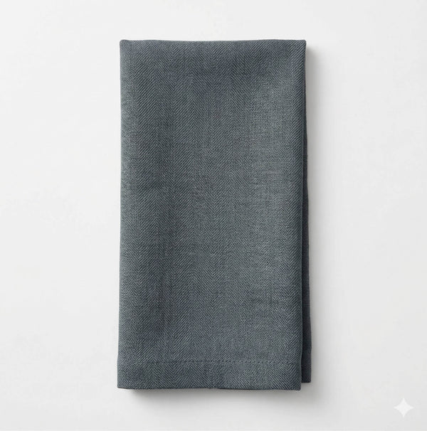 A neatly folded Amelia Jade Green Linen napkin with a subtle herringbone pattern, set against a plain white background—an elegant fabric choice for any event.