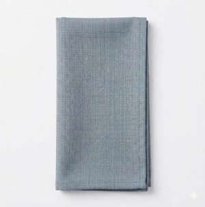 The Amelia Light Blue Linen napkin, elegantly textured and neatly folded, adds a refined fabric accent to any event decor. Displayed on a white background for sophisticated style.