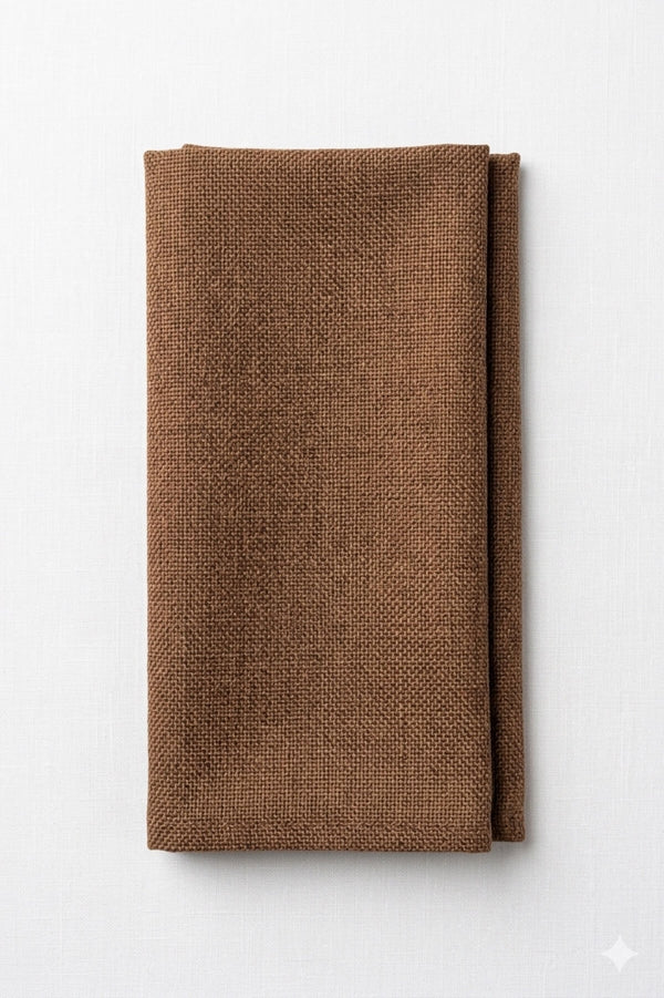 An Amelia Milk Brown Linen napkin is neatly folded and placed on a white surface, adding an elegant fabric touch to any event setting.