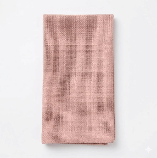 A neatly folded Amelia Pink Linen napkin rests on a plain white background, showcasing elegant textured fabric perfect for elevating any event setting.