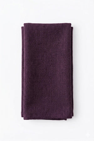 A neatly folded Amelia Purple Linen napkin, featuring a dark purple textured design and elegant fabric, is displayed on a plain white background.