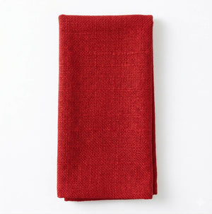 A neatly folded Amelia Red Linen napkin rests on a white surface, offering a refined textured accent ideal for elevating any event setting.