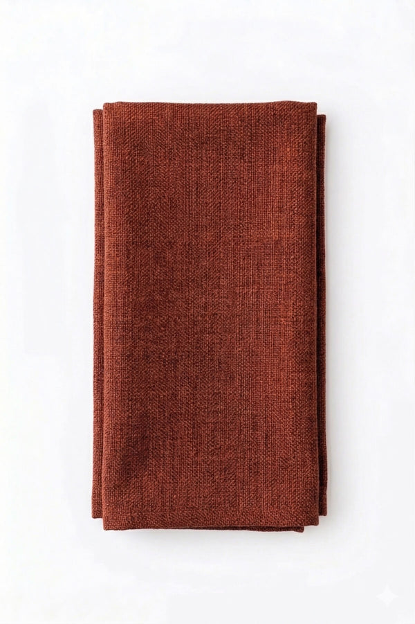 A neatly folded Amelia Rust Linen napkin with a rich texture rests on a white background, adding an elegant fabric touch to any event setting.
