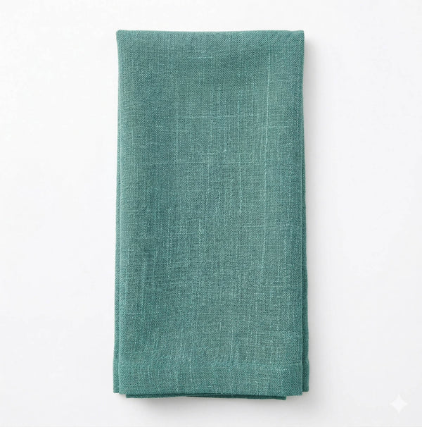 A neatly folded Amelia Sea Green Linen napkin, made from elegant fabric, sits on a plain white surface.