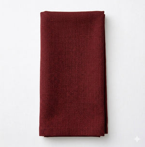 A neatly folded, textured dark red cloth napkin made from Amelia Soft Red Linen is placed on a plain white background.