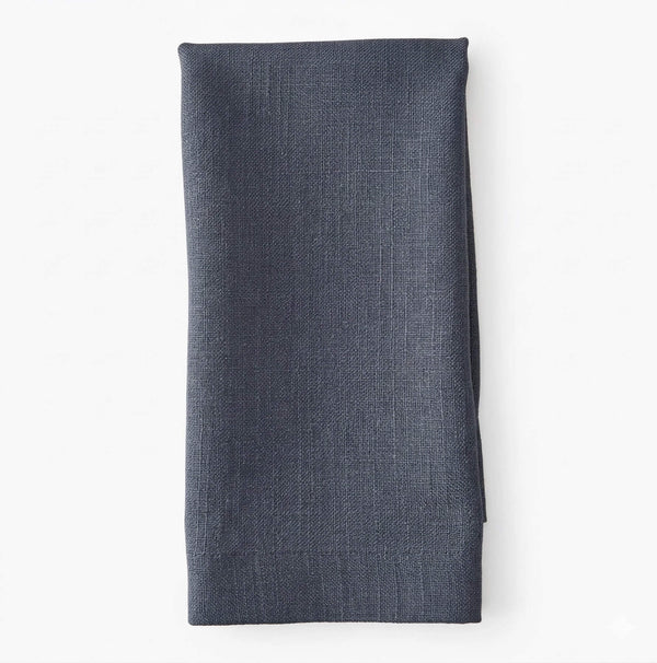 A neatly folded Amelia Steel Blue Linen napkin, crafted from elegant fabric, is displayed against a plain white background.
