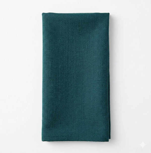 The Amelia Yucca Linen is a dark teal cloth napkin, neatly folded to showcase its elegant linen fabric and subtle herringbone pattern, displayed on a white background.