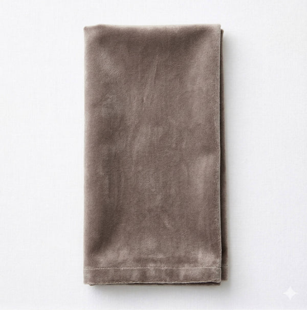 A neatly folded Charlotte Ash Grey Velvet napkin is placed on a light surface, showcasing its soft texture and subtle sheen.
