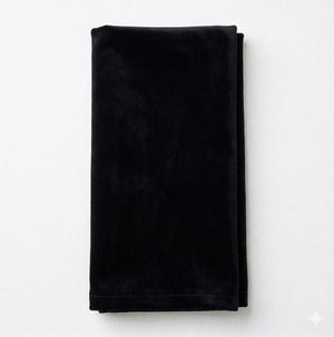 The Charlotte Black Velvet napkin, crafted from luxurious velvet, is neatly folded and displayed on a plain white surface.