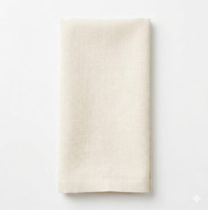 The Charlotte Cream Velvet napkin, elegantly folded, rests on a white surface and is viewed from above.