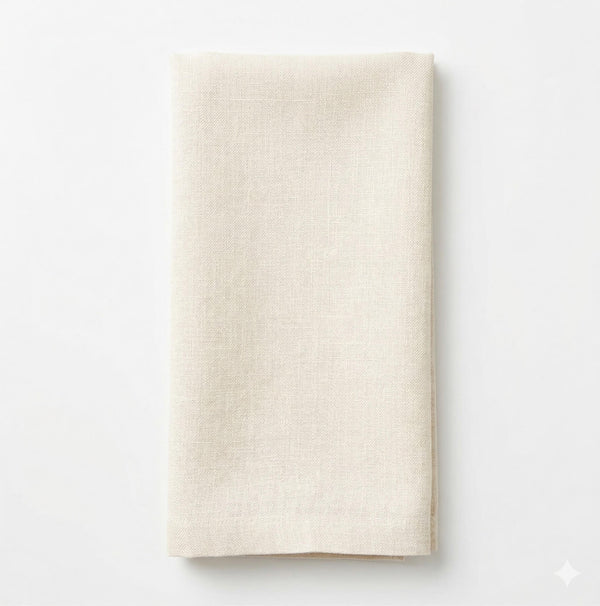 The Charlotte Cream Velvet napkin, elegantly folded, rests on a white surface and is viewed from above.