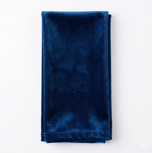 Charlotte Dark Blue Velvet, a neatly folded rich blue luxurious fabric, rests on a white background—perfect for adding sophistication and elegance to any event decor.