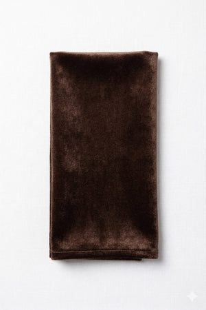 A Charlotte Dark Brown Velvet napkin, neatly folded, is displayed on a white background.