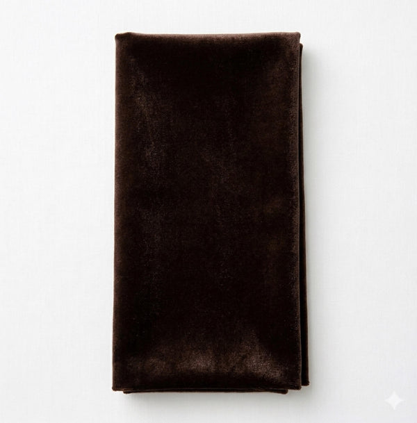 A Charlotte Dark Chocolate Velvet napkin is neatly folded and placed on a white surface.