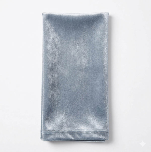A neatly folded, rectangular Charlotte Light Blue Velvet napkin is displayed on a plain white background, emphasizing its elegant velvet fabric.