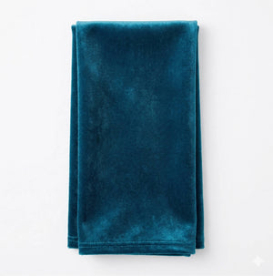 A neatly folded Charlotte Soft Blue Velvet fabric rests on a white surface, highlighting its soft, plush texture and rich blue hue.