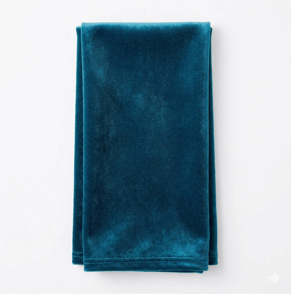 A neatly folded Charlotte Soft Blue Velvet fabric rests on a white surface, highlighting its soft, plush texture and rich blue hue.