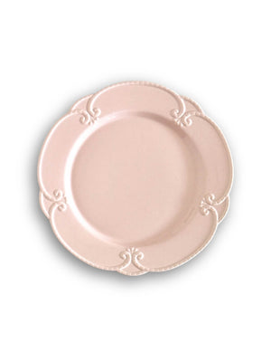 The Annalise Pink Plate Range features round blush pink plates with scalloped edges and embossed scroll patterns at four points, evoking vintage romance on a white background.