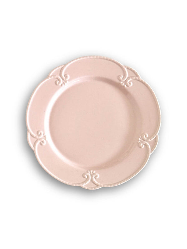 The Annalise Pink Plate Range features round blush pink plates with scalloped edges and embossed scroll patterns at four points, evoking vintage romance on a white background.