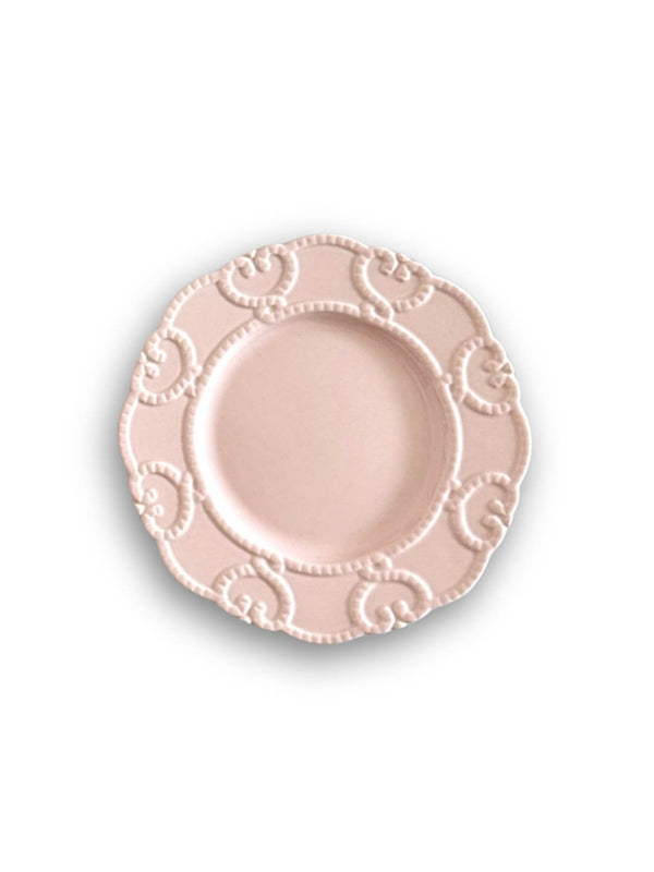 A round, blush pink Annalise Pink Plate Range plate with a scalloped edge and embossed swirl and dot details evokes vintage romance, displayed on a white background.