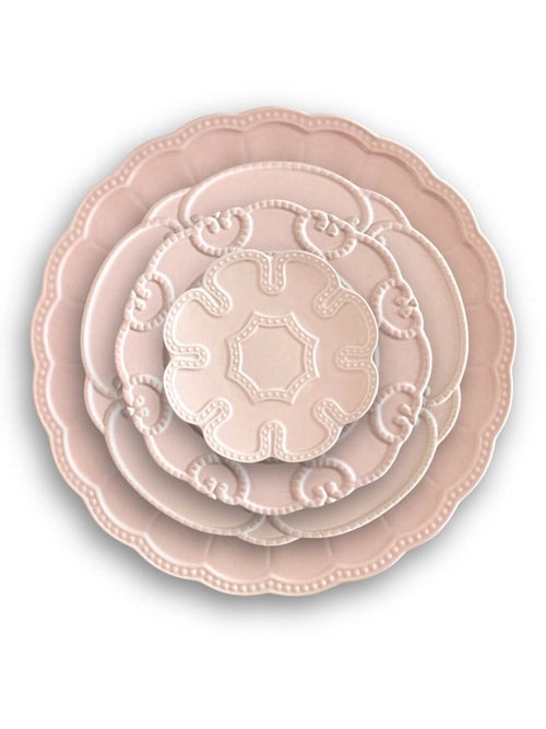 Three stacked Annalise Pink Plate Range pieces, each blush pink with embossed designs and scalloped edges, evoke vintage romance. Each plate is smaller than the one below for a classic, timeless look.