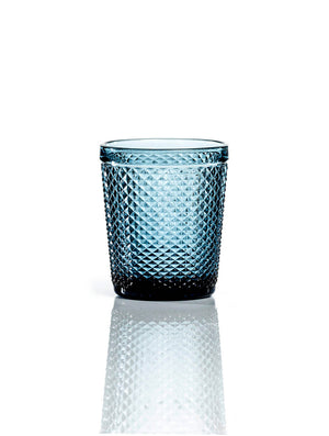 The Apiary Blue Tumbler features a diamond-patterned, honeycomb textured glass in blue, shown against a white background with its reflection—a stylish and elegant upgrade to any glassware collection.