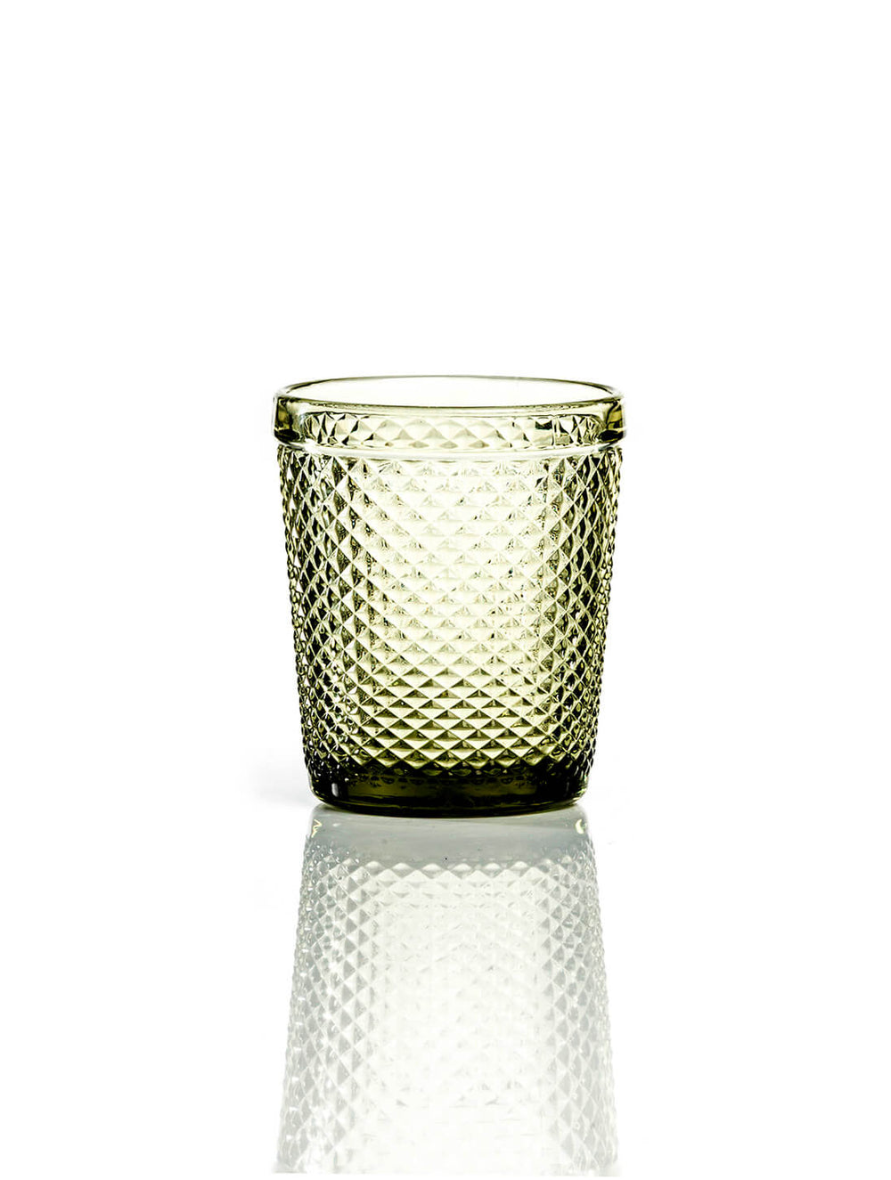 The Apiary Olive Tumbler features a textured, transparent finish with a diamond pattern and sits on a white surface, its reflection visible—perfect as honeycomb glass for rustic wedding decor.
