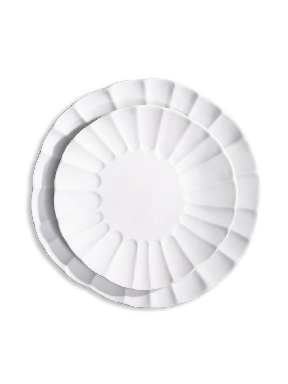 Two white porcelain plates from the Babble Plate Range, one nested inside the other, feature scalloped edges and a petal-like rim design—a refined choice for elegant dining.