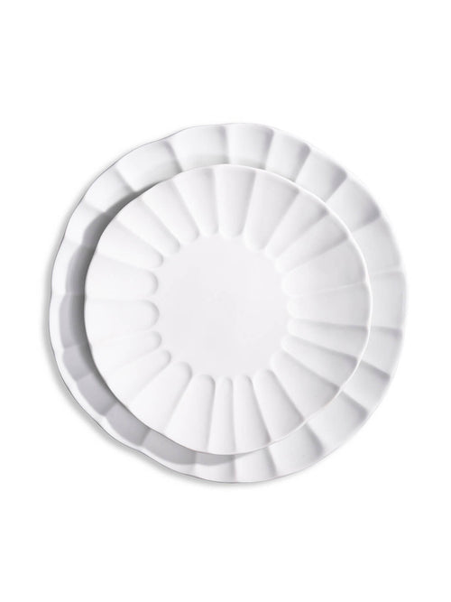 Two white porcelain plates from the Babble Plate Range, one nested inside the other, feature scalloped edges and a petal-like rim design—a refined choice for elegant dining.