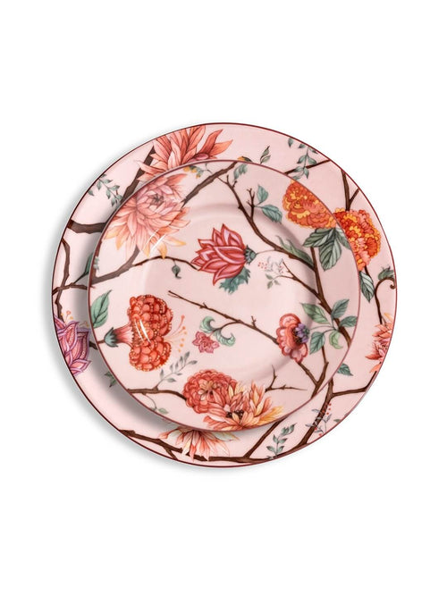 The Botanic Pink Plate Range features two round ceramic plates with a pink background, vibrant floral patterns in red, orange, and pink, green leaves, and brown branches—perfect for elevating your pink tableware.