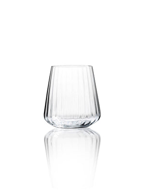 A clear glass tumbler from the Catherine Glassware Range, featuring a tapered shape and vertical ripple pattern, sits on a reflective white surface—ideal for luxury weddings and elegant gatherings.