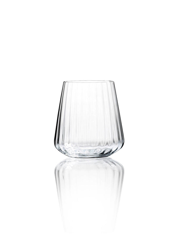 A clear glass tumbler from the Catherine Glassware Range, featuring a tapered shape and vertical ripple pattern, sits on a reflective white surface—ideal for luxury weddings and elegant gatherings.