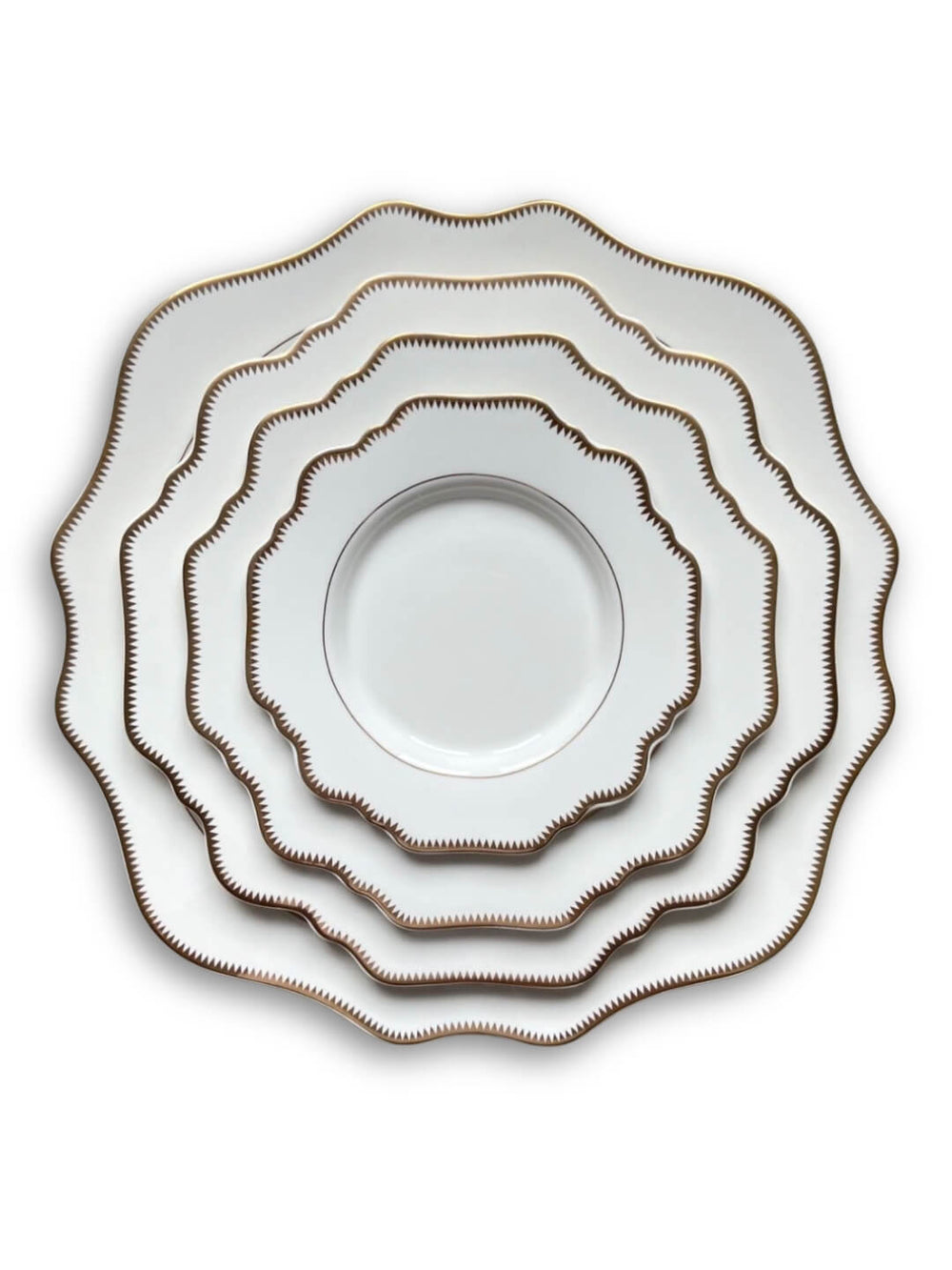Five plates from the Colette White Plate Range, featuring scalloped edges and gold zigzag rims, are stacked concentrically on a white background for a timelessly sophisticated look.