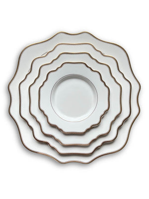 Five plates from the Colette White Plate Range, featuring scalloped edges and gold zigzag rims, are stacked concentrically on a white background for a timelessly sophisticated look.