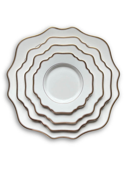 Five plates from the Colette White Plate Range, featuring scalloped edges and gold zigzag rims, are stacked concentrically on a white background for a timelessly sophisticated look.