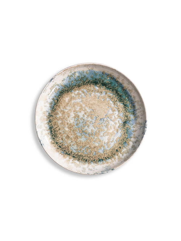 The Cove Plate Range features a round ceramic plate with a textured, mottled pattern in beige, blue, and green tones. Its earthy, abstract design highlights artisanal craftsmanship. Shown from above on a white background.