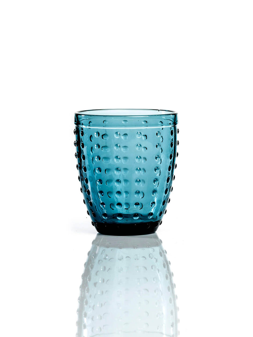 The Dotty Blue Tumbler boasts a raised dot texture on vibrant blue glass, bringing modern style to any table and standing out beautifully on a white surface.
