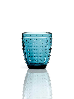 The Dotty Blue Tumbler boasts a raised dot texture on vibrant blue glass, bringing modern style to any table and standing out beautifully on a white surface.