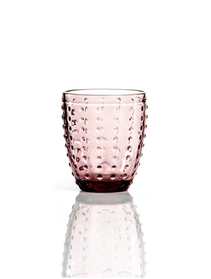 The Dotty Pink Tumbler features a textured dotted pattern in pink glass, standing upright on a reflective white surface—ideal for adding charming style to your wedding tableware collection.